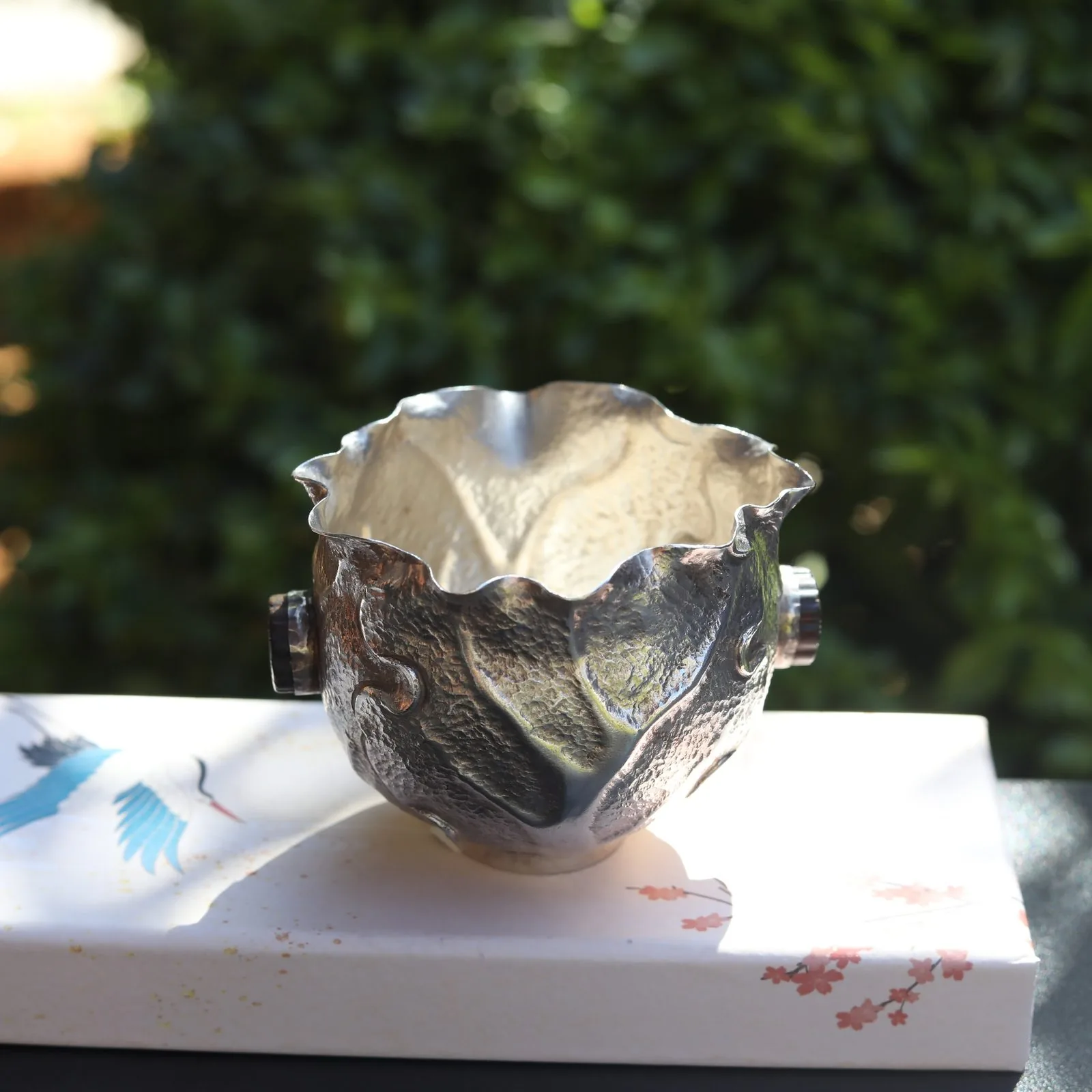 Petal-rim silver cup with leaf relief on a pale base