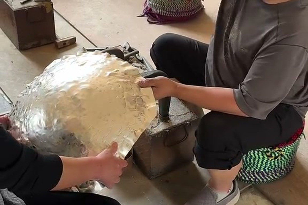 An artisan shaping metal at a workshop bench