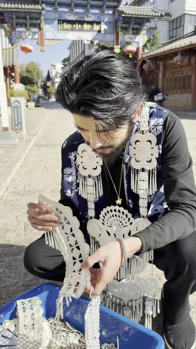 Mr. Jiang wearing a full set of silver jewelry under a silver archway
