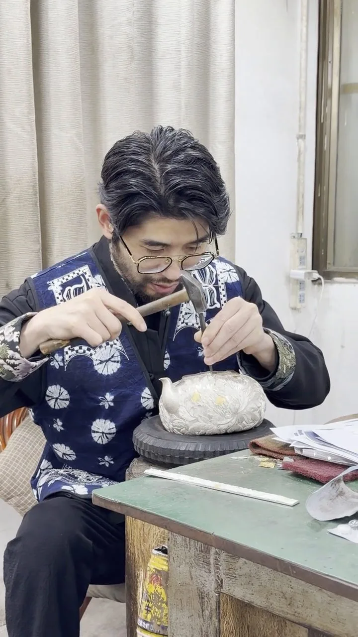 Silversmith chasing a teapot — every piece starts at a bench like this