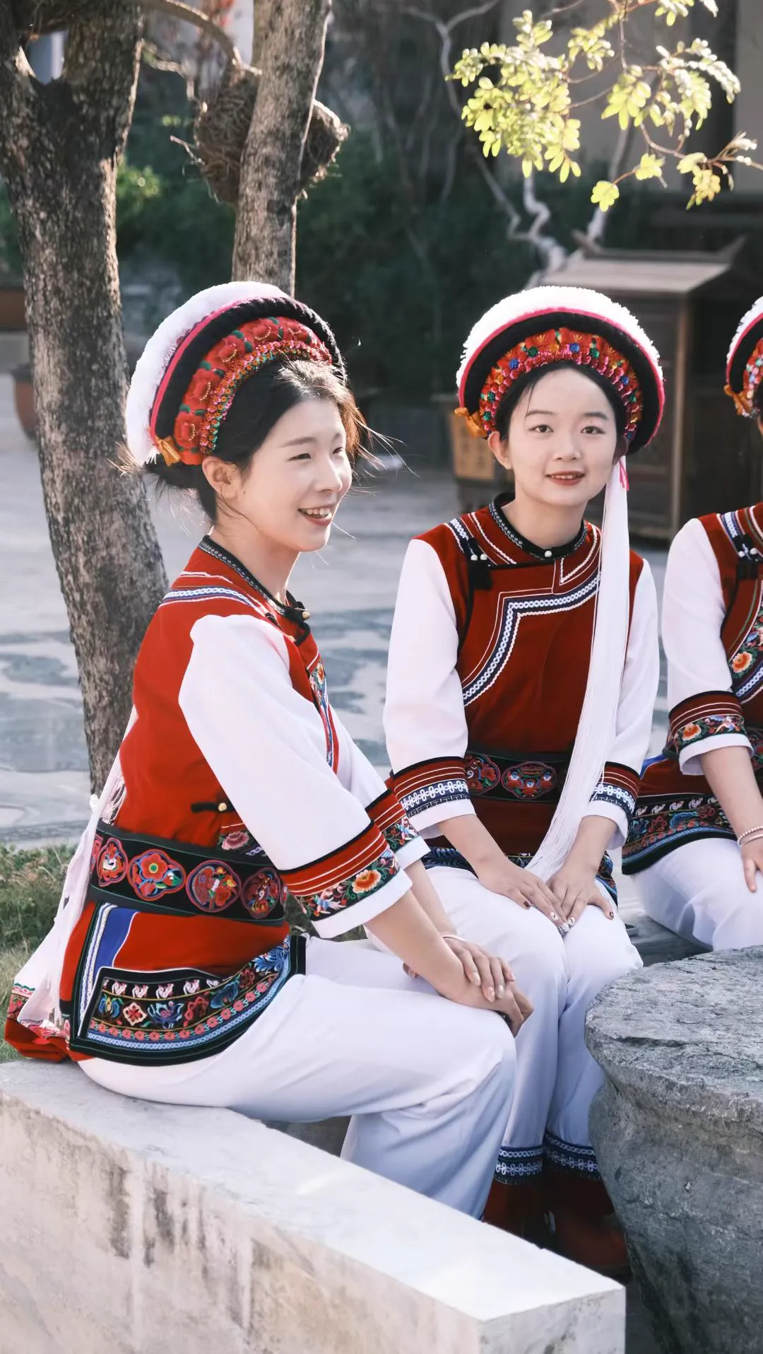 Two Bai girls sitting on a stone bench
